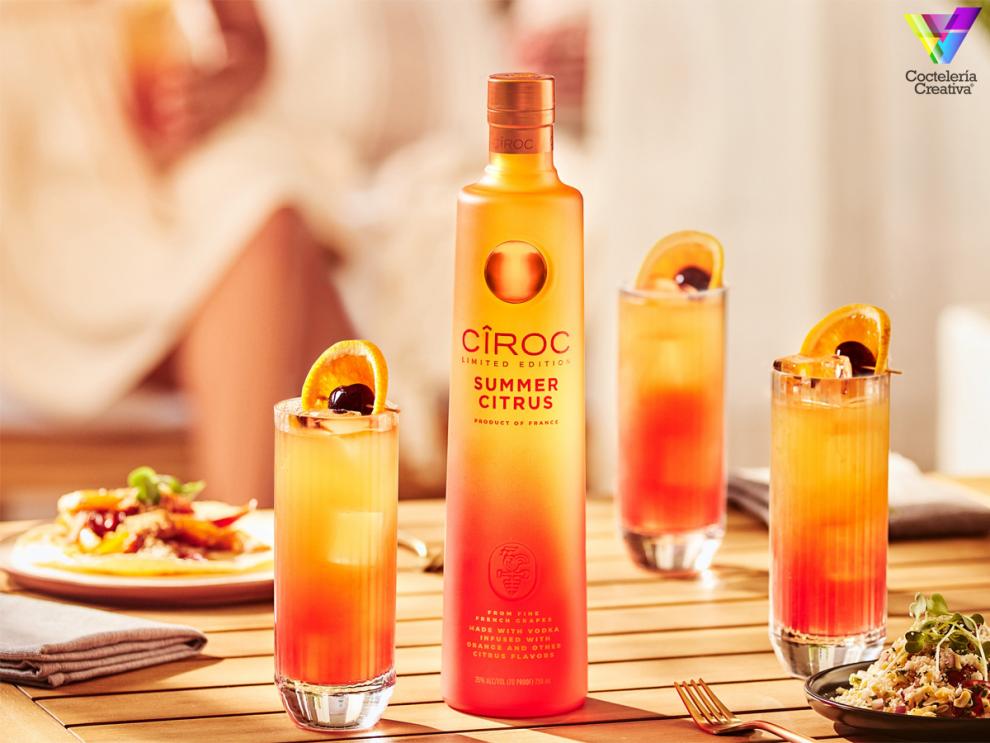 Botella de Cîroc Summer Citrus con cocktails decorados con naranja y cereza