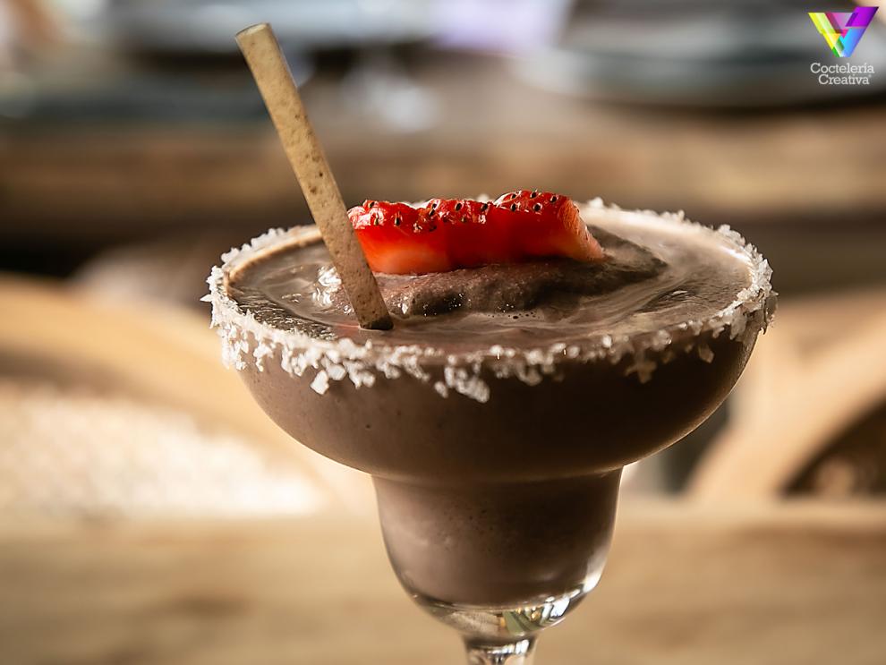 Cóctel Margarita Mestizo con Cacao Azteca con rayadura de coco y láminas de fresa, decorado con cristales de sal