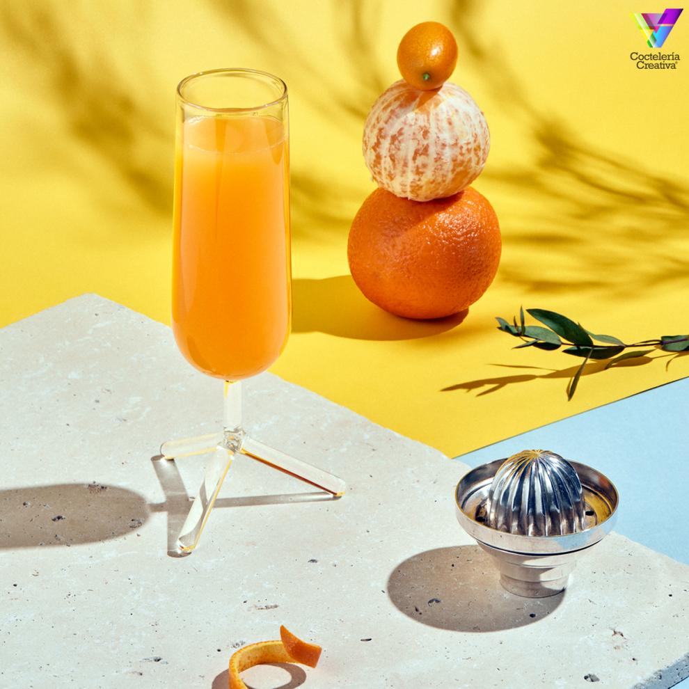 Copa con cóctel y naranjas apiladas detrás sobre fondo naranja Copa con cóctel y naranjas apiladas detrás sobre fondo naranja
