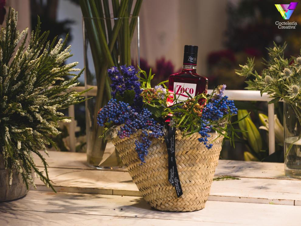 Canasta con arreglo floral y botella de Pacharán Zoco Canasta con arreglo floral y botella de Pacharán Zoco
